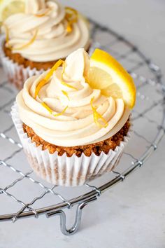 two cupcakes with lemon and icing on a wire rack