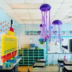 an empty classroom with desks, chairs and jellyfish decorations hanging from the ceiling