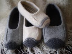 two pairs of slippers sitting on top of a white and gray blanket next to each other