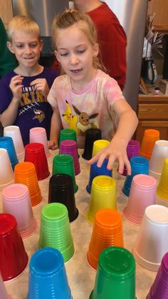 two children are playing with cups on the table