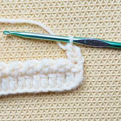 the crochet hook is being used to hold the knitting stitchs in place