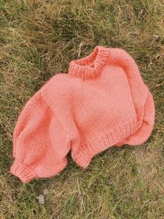 an orange knitted sweater laying on the grass