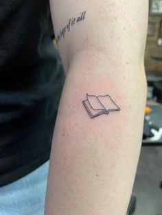 a person with a book tattoo on their arm