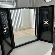 two black mirrors sitting on top of a white table next to a wall mounted clock