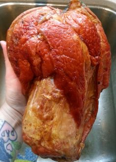 a person holding up a piece of meat in a metal pan