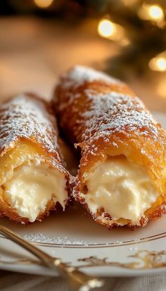 two pastries sitting on top of a white plate next to a fork and christmas tree