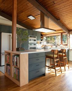 a kitchen with wooden floors and an island that has chairs around it in front of the counter