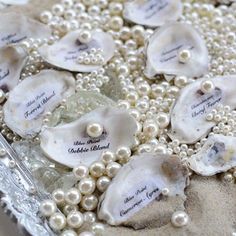 pearls and sea shells are arranged in a glass dish on the table with place cards