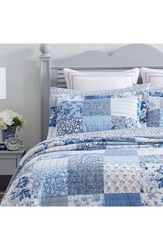 a blue and white quilted comforter set on top of a bed with pillows