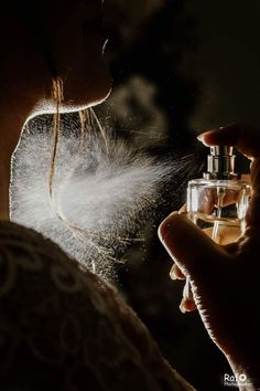 a woman is smelling the spray from her perfume bottle