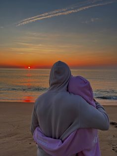 a person sitting on the beach watching the sunset