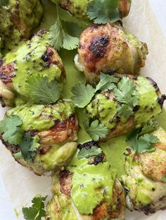 chicken with green sauce and cilantro garnish on parchment paper, ready to be eaten