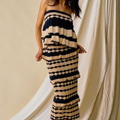 a woman standing in front of a white backdrop wearing a black and tan striped dress