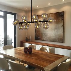 a dining room table with white chairs and a large painting on the wall behind it