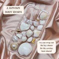 two cowboy boot charms are sitting in a clear case on a pink satin surface