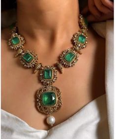 This exquisite Victorian doublets statement necklace set in emerald green captures the essence of opulence and vintage charm. The necklace, crafted with meticulous detail, features gleaming emerald green doublets set in an ornate Victorian-style framework. Each doublet, with its rich hue and intricate facets, reflects light beautifully, creating a mesmerizing play of colors.  The necklace cascades gracefully, adorned with smaller emerald accents and delicate filigree patterns that evoke the grandeur of the Victorian era. Its length ensures it sits elegantly on the neckline, making it a striking centerpiece for formal occasions or elegant evenings. Accompanying the necklace are matching earrings that echo its design, with emerald doublets framed by intricate metalwork that enhances their al Emerald Jewelry Necklace, Victorian Jewelry Necklace, Filigree Jewellery, Emerald Necklaces, Sabyasachi Jewelry, Victorian Style Jewelry, Long Necklace Set, Victorian Jewellery, Necklace Set With Earrings