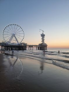 a ferris wheel sitting on top of a beach next to the ocean