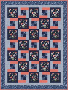 a blue and pink quilt with flowers on the front, along with an orange border