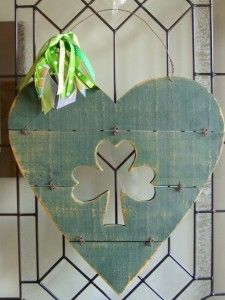 a heart shaped sign hanging on the side of a wall next to a green bow