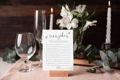 a place card sitting on top of a table next to two wine glasses and candles