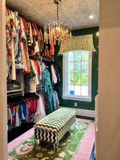 the closet is filled with clothes and chandelier hanging from it's ceiling