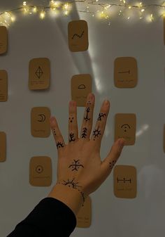 a person's hand with many symbols on it and some string lights behind them