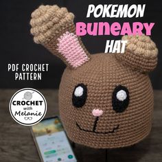 a crochet pokemon bunny hat sitting on top of a table next to a cell phone