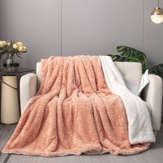 a couch with a blanket on it in front of a wall and potted plant