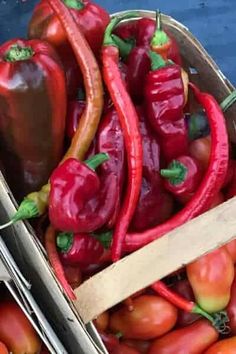 red and yellow peppers are in a wooden box