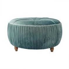 a round ottoman with wooden legs and a green velvet cover on the top, sitting in front of a white background