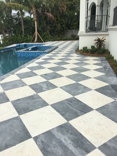 a large checkerboard tile patio next to a swimming pool in a tropical setting