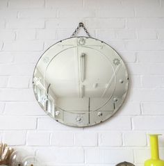 a white brick wall with a round mirror hanging on it's side next to other decorative items