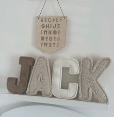 the word jack spelled out in front of a white wall with a wooden sign hanging above it