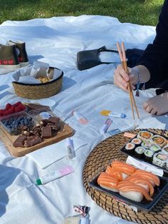 a person sitting at a table with sushi and chopsticks