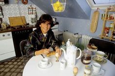 a person sitting at a table with some food in front of them and cups on the table