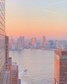 a boat is in the water next to tall buildings and skyscrapers at sunset or dawn