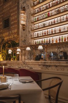 an empty restaurant with many bottles on the wall and tables in front of it,