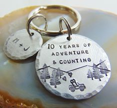 two metal key chains with the words 10 years of adventure and counting on them