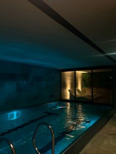 an indoor swimming pool at night with lights shining on the walls and water running through it