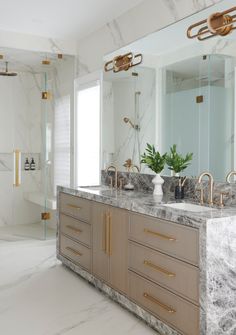 a large bathroom with marble counter tops and gold faucets on the vanity top