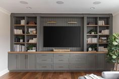 a large entertainment center with built in bookshelves and shelves on each side, along with a flat screen tv mounted to the wall