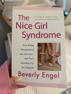 the nice girl syndrome book is being held by a woman's hand with her shoes on