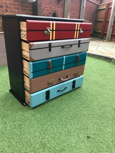 four suitcases stacked on top of each other in front of a brick wall and green grass