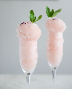 two glasses filled with ice cream and mint sprinkled on top of each other