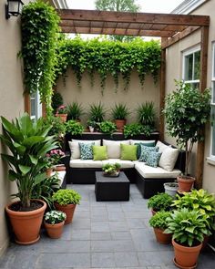 an outdoor living area with potted plants and couches on the side of the building