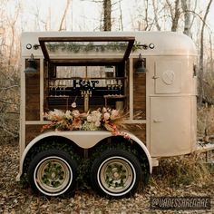 an old fashioned food truck is decorated with flowers and greenery on the front wheel