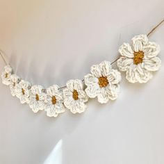 white crocheted flowers are hanging from a string