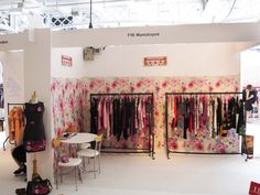 a room filled with lots of clothes on display in front of a white table and chairs