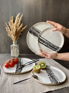 two plates with black and white designs on them, one is holding a kiwi