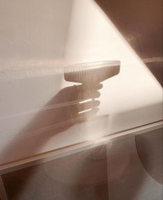 the shadow of a person's hand on top of a glass table with a light shining through it